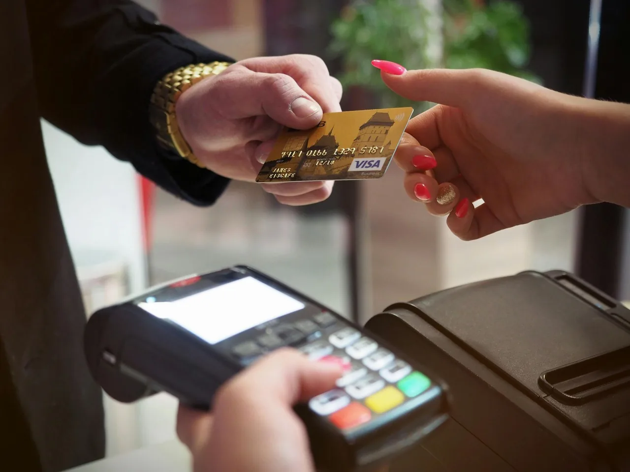Customer handing over a payment card beside a card reader.