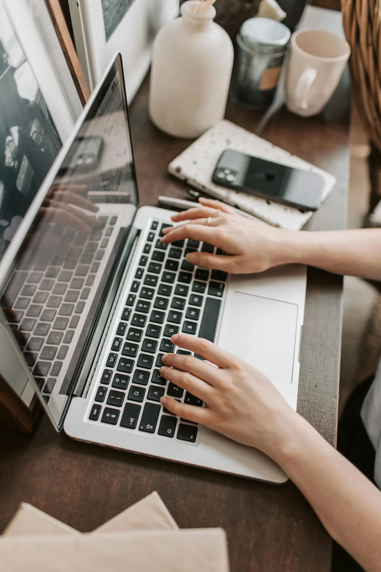 Hands typing on a laptop at a desk.